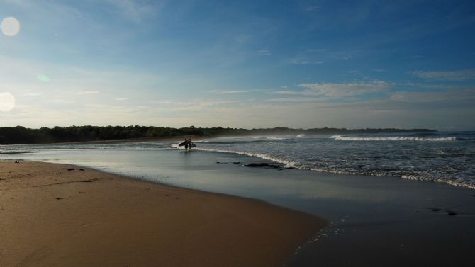 Surfers walking out to the surf at Playa Langosta near Tamarindo