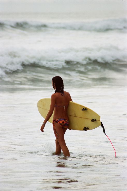 Girl surfer going to get surf at Santa Teresa