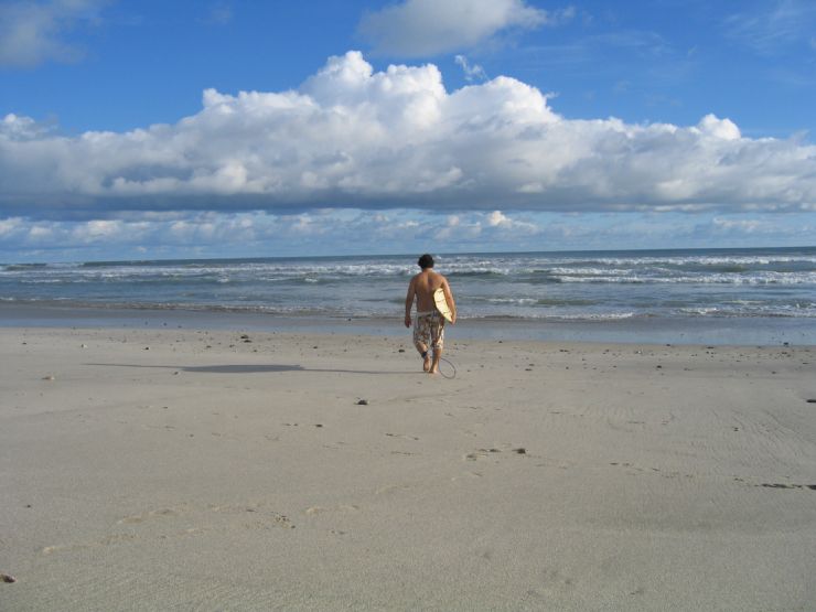 Surfer walking out to blown out surf