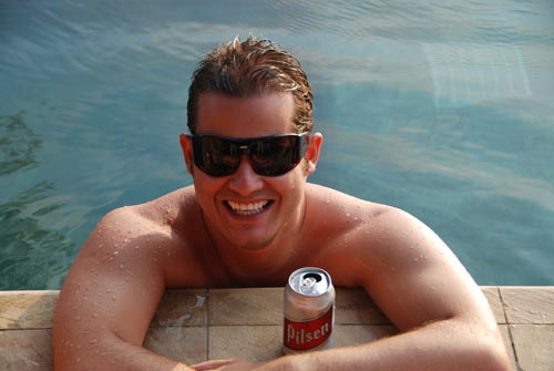 Javier enjoying a beer at a pool